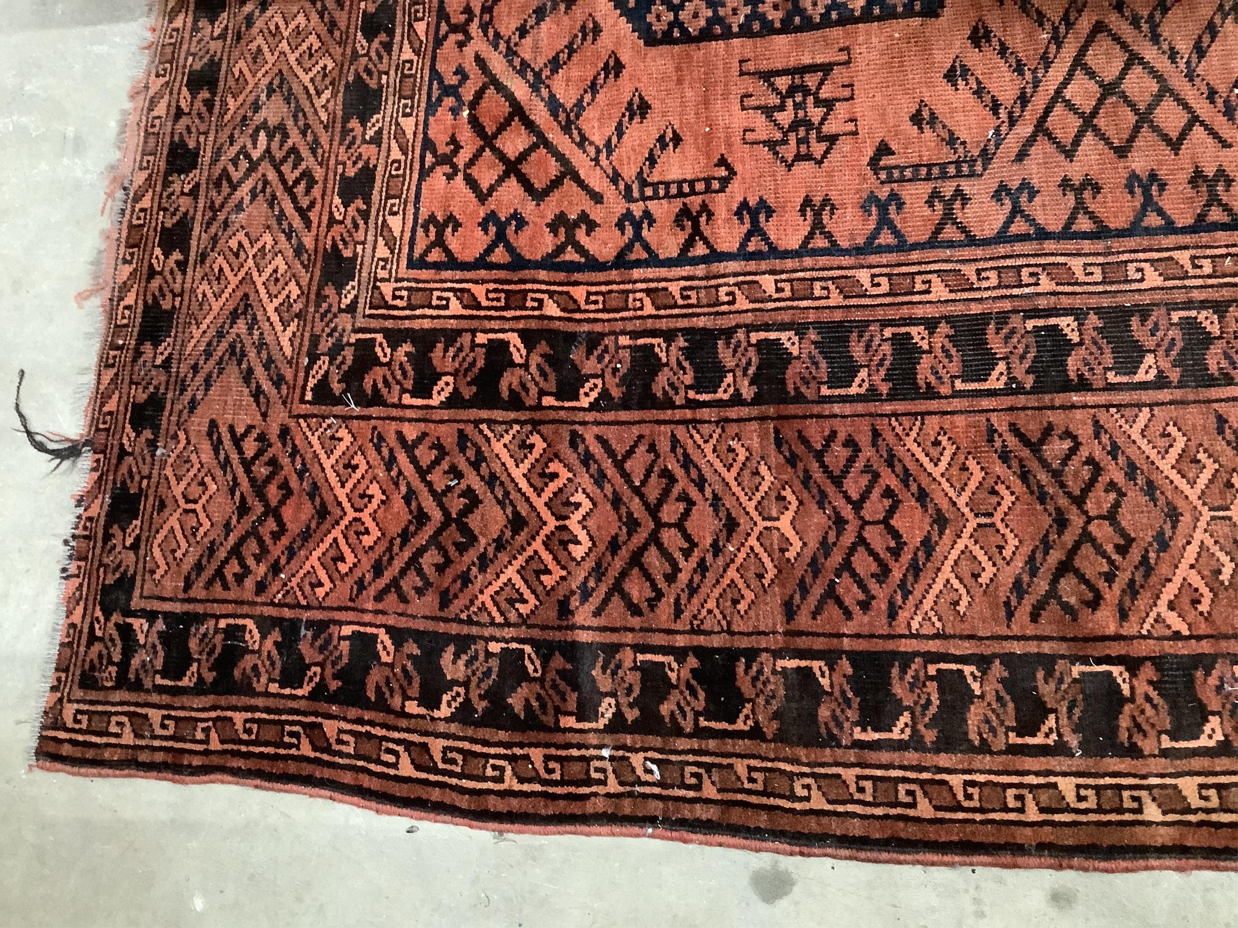 An Afghan rust ground carpet, 400 x 260cm. Condition - poor, damage to border